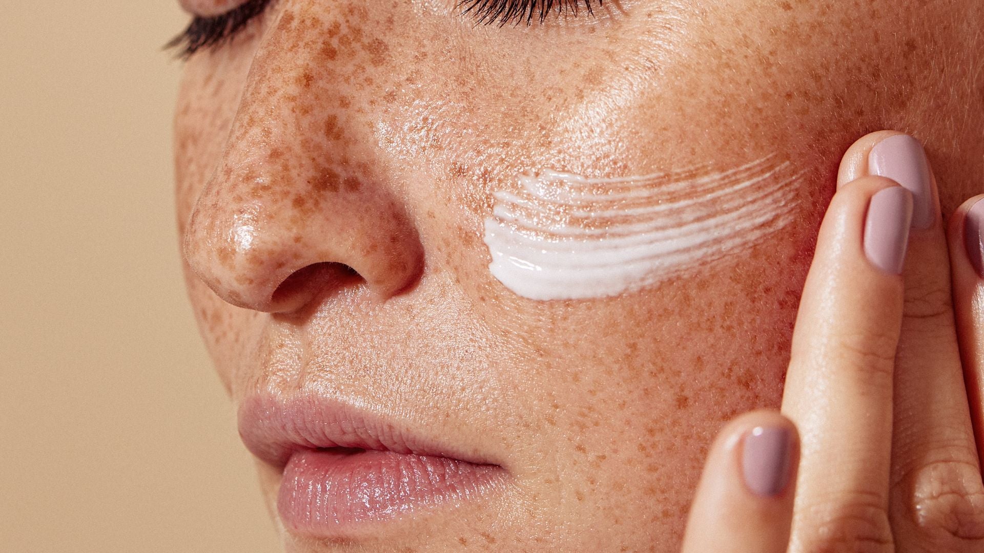 Application d'une crème hydratante sur le visage, illustrant une routine de soin de la peau.