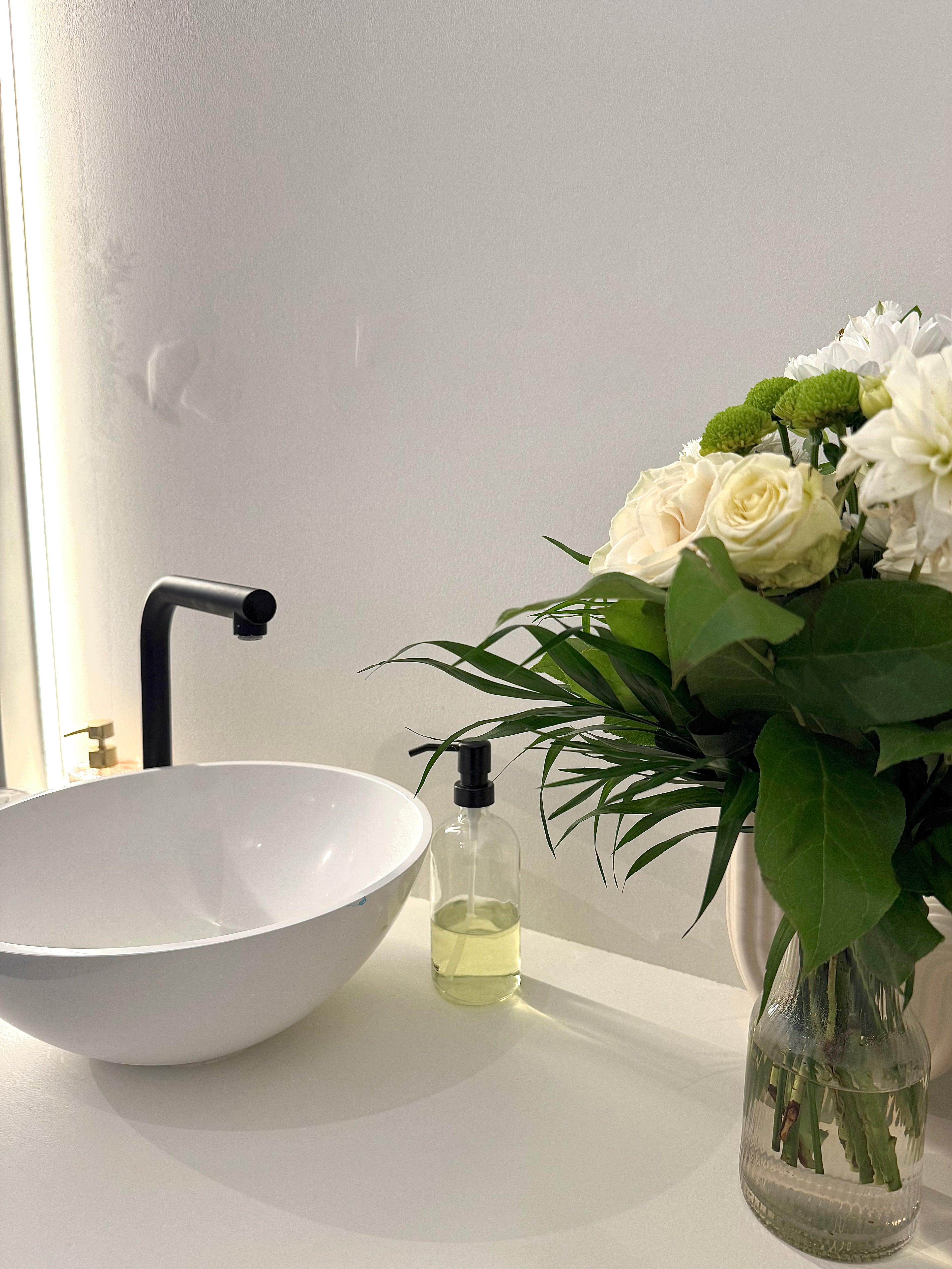 Coin du cabinet de Lohanne Charvet à Chaponost, avec vasque moderne, bouquet de fleurs et ambiance douce pour accueillir les patients.