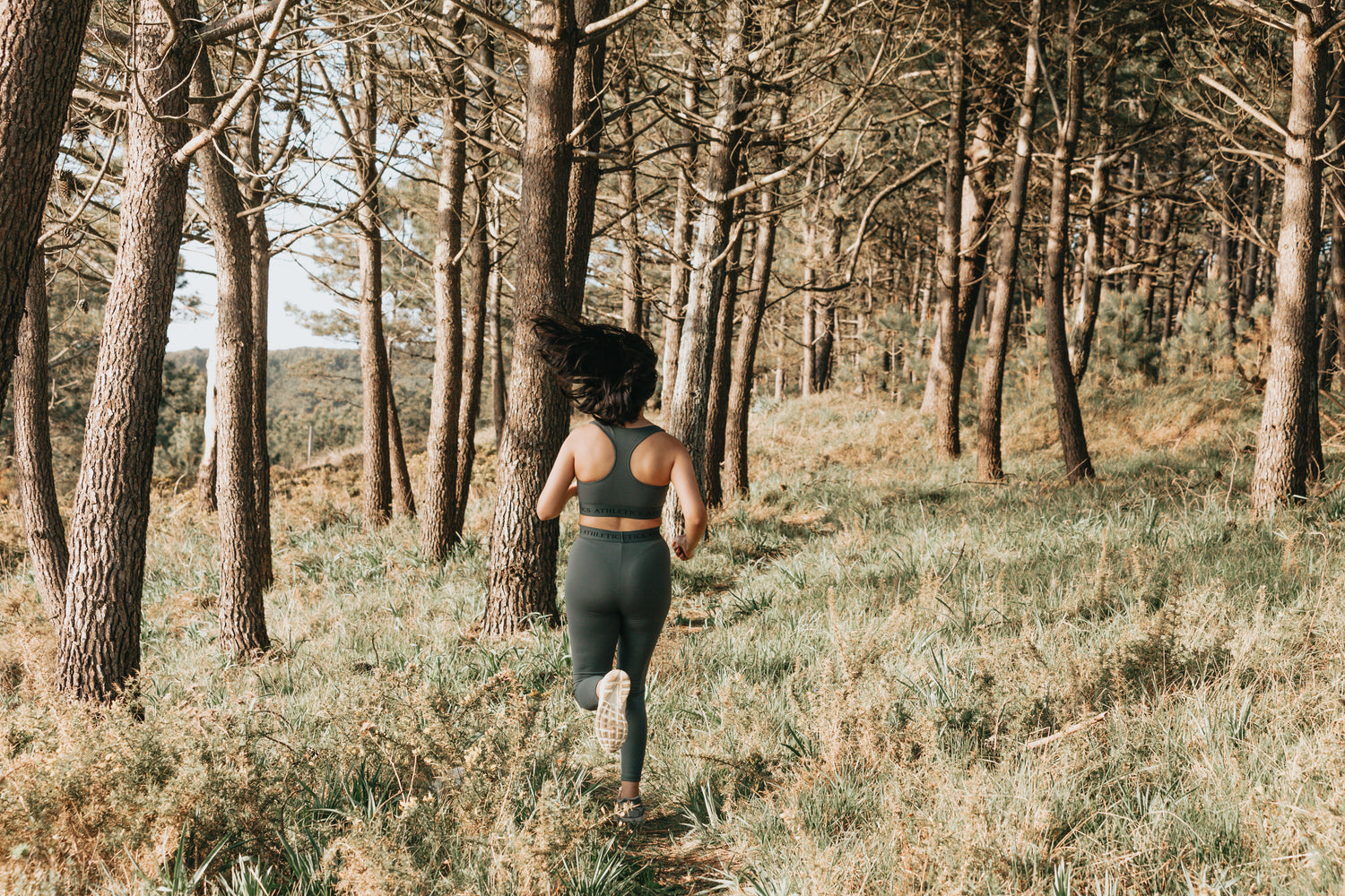Femme en train de courir en forêt, illustrant l’accompagnement ostéopathique des sportifs pour prévenir les blessures et améliorer la récupération.